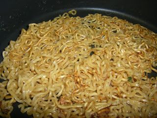 noodles are being cooked in a wok on the stove top, ready to be eaten