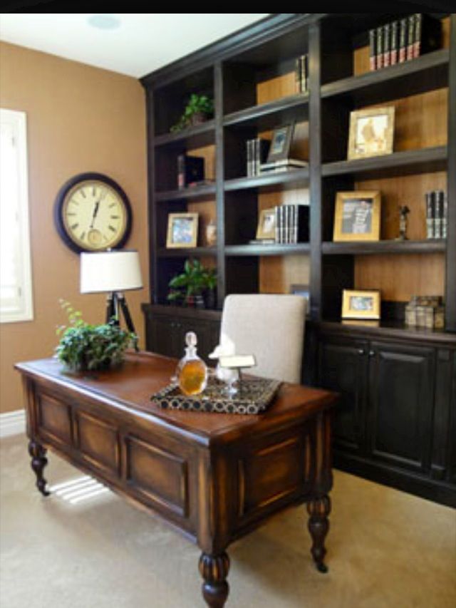 an office with a desk, bookshelf and clock