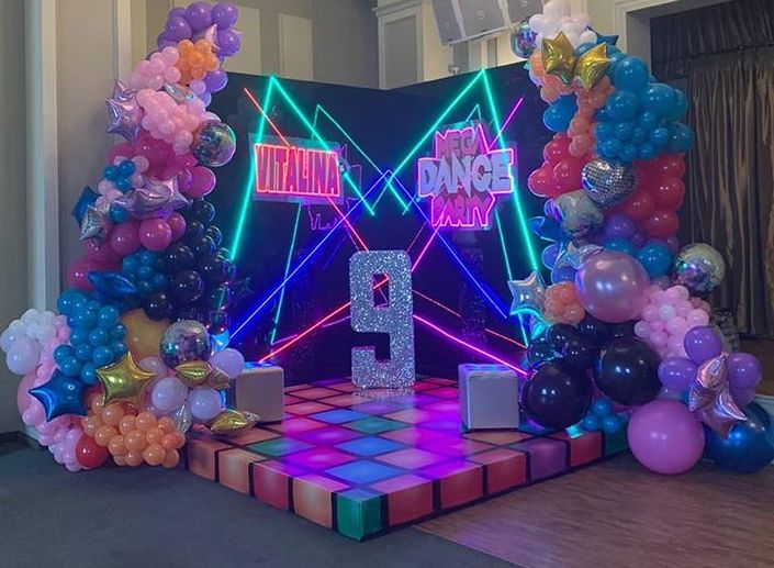 a stage set up with balloons and decorations for a birthday party at the same time