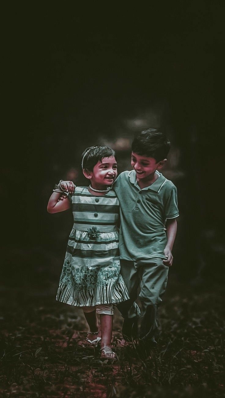 two young boys standing next to each other in the dark with their arms around each other