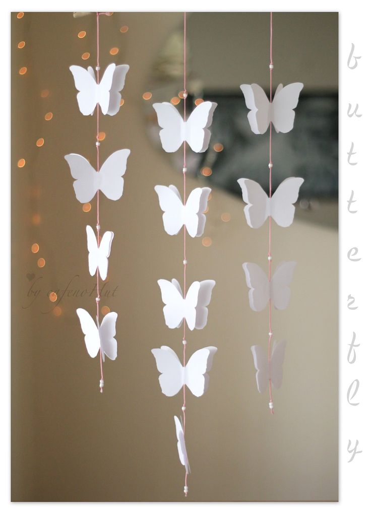 some white paper butterflies hanging from strings