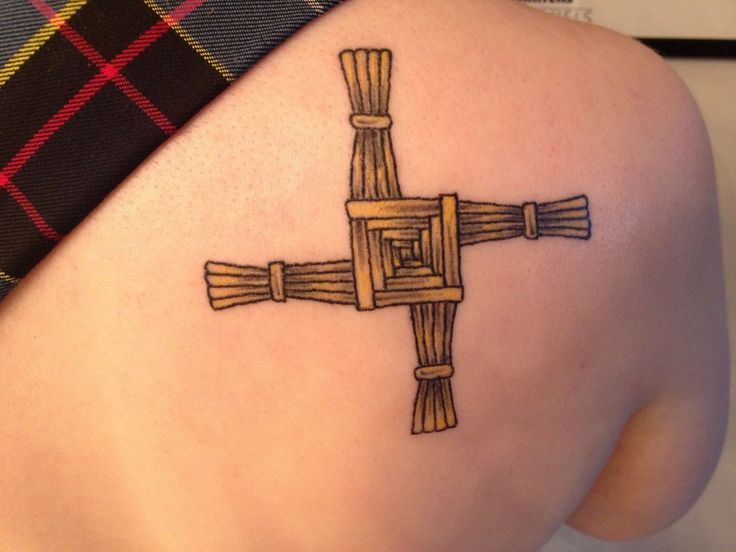 a cross tattoo on the back of a woman's shoulder, with bamboo sticks sticking out of it