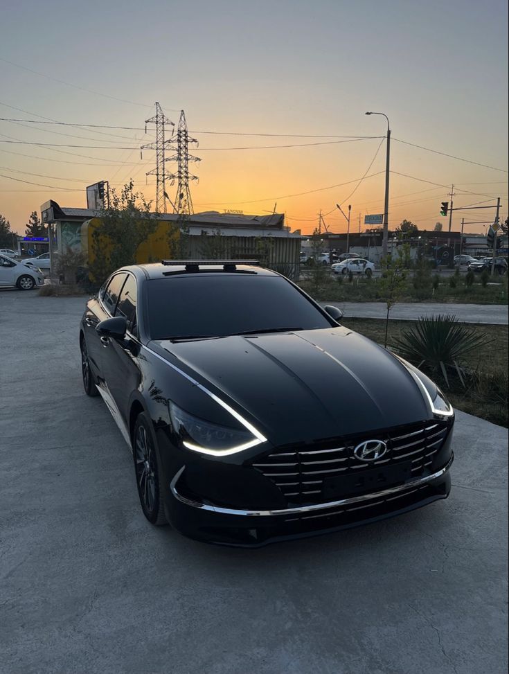 a black car parked in a parking lot at sunset