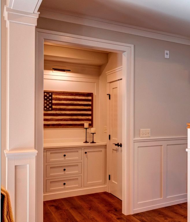 an open door leading to a kitchen with white cabinets and american flag on the wall