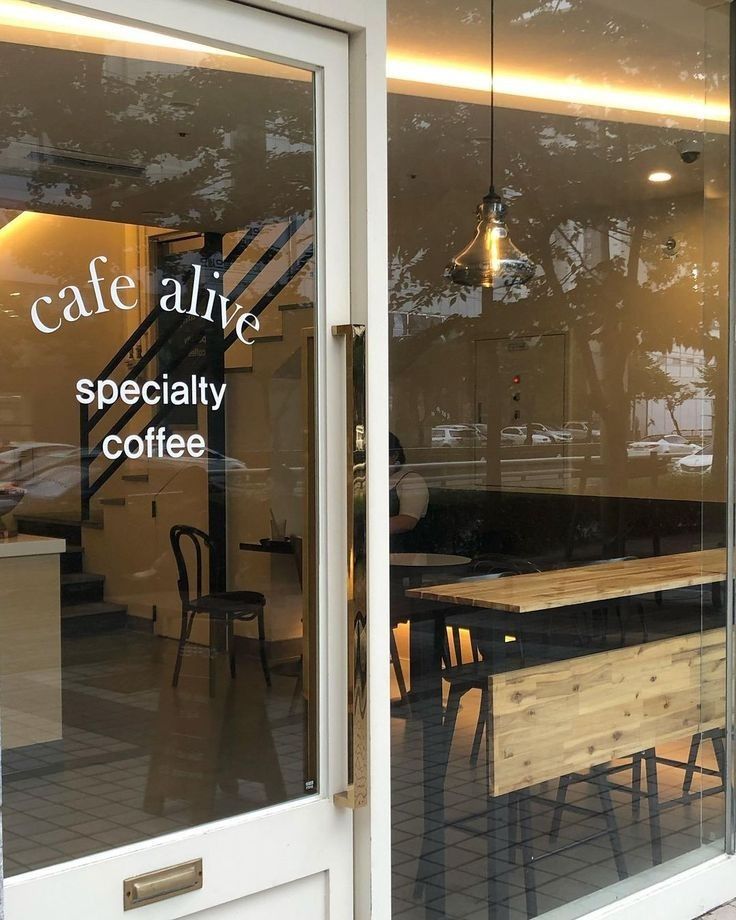 the front window of a coffee shop with wooden tables and chairs in it's glass doors