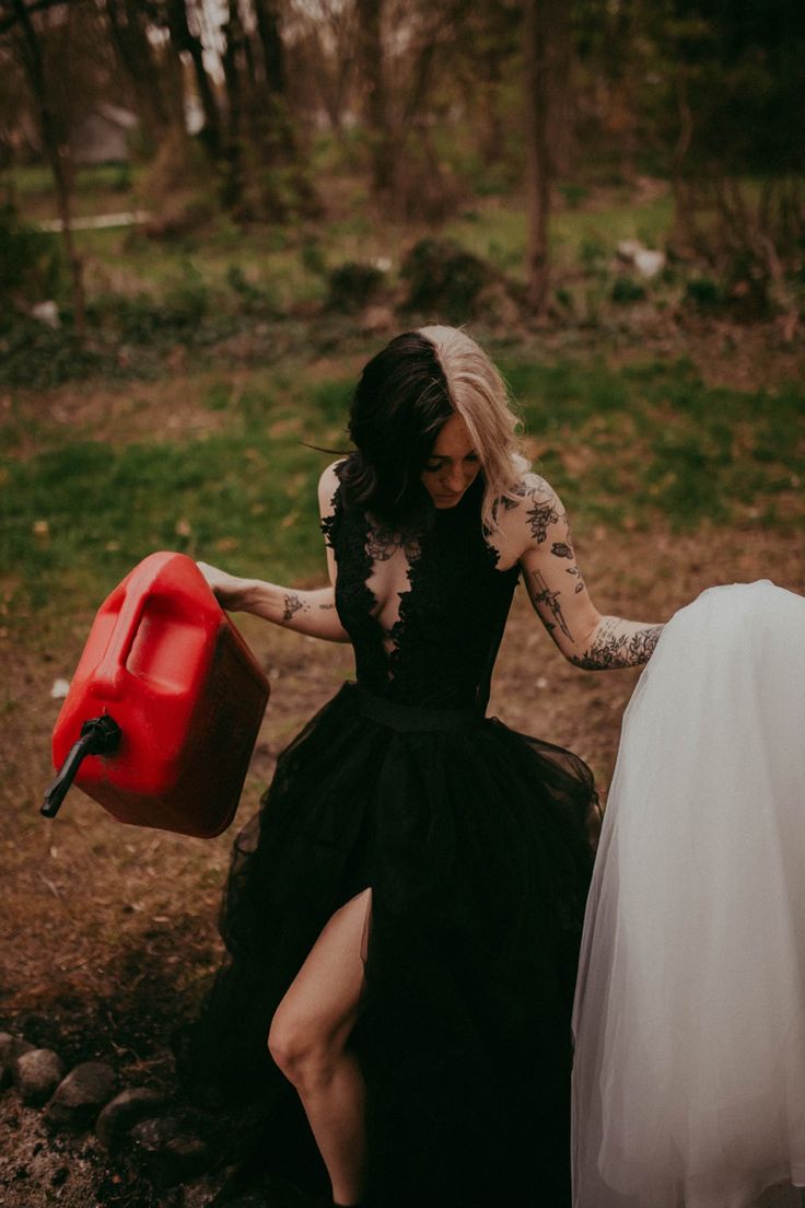 a woman in a black dress holding a red barrel