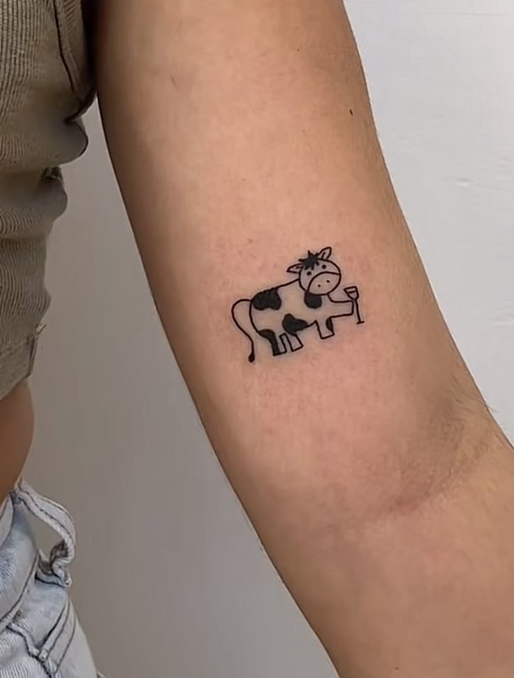 a small cow tattoo on the arm