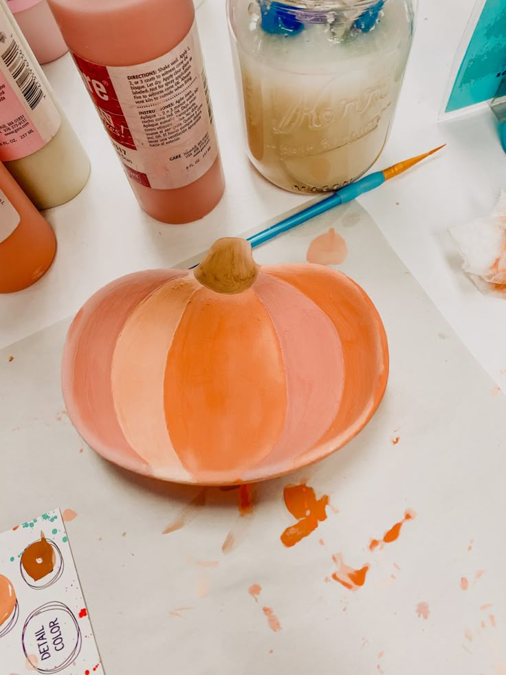 an orange pumpkin sitting on top of a table next to some paint and other crafting supplies