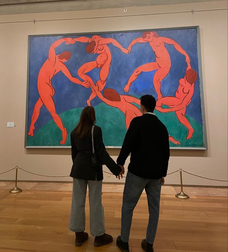 two people standing in front of a large painting on display at an art museum, holding hands