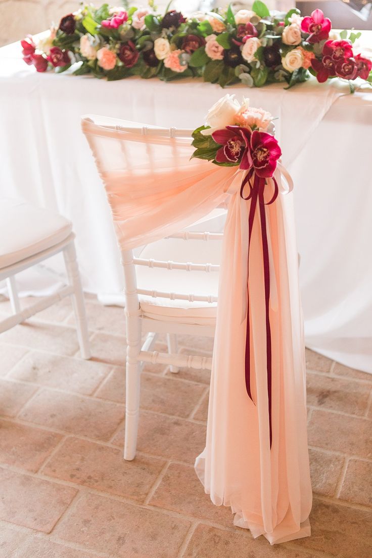 a chair with a bow tied to it sitting next to a table covered in flowers