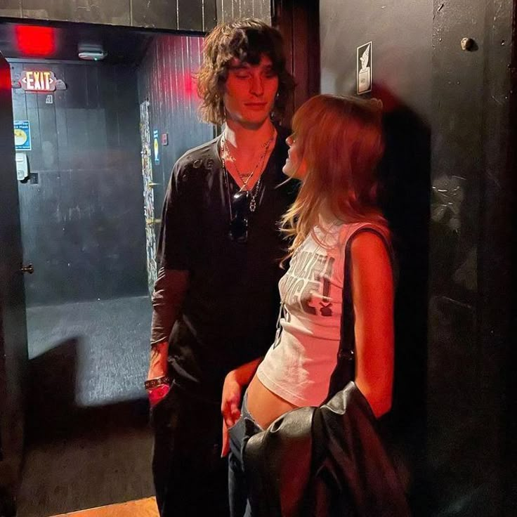 a man and woman standing next to each other in front of a wall with an elevator