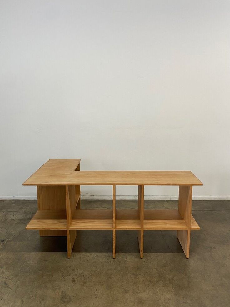 two wooden benches sitting next to each other on top of a cement floor in front of a white wall