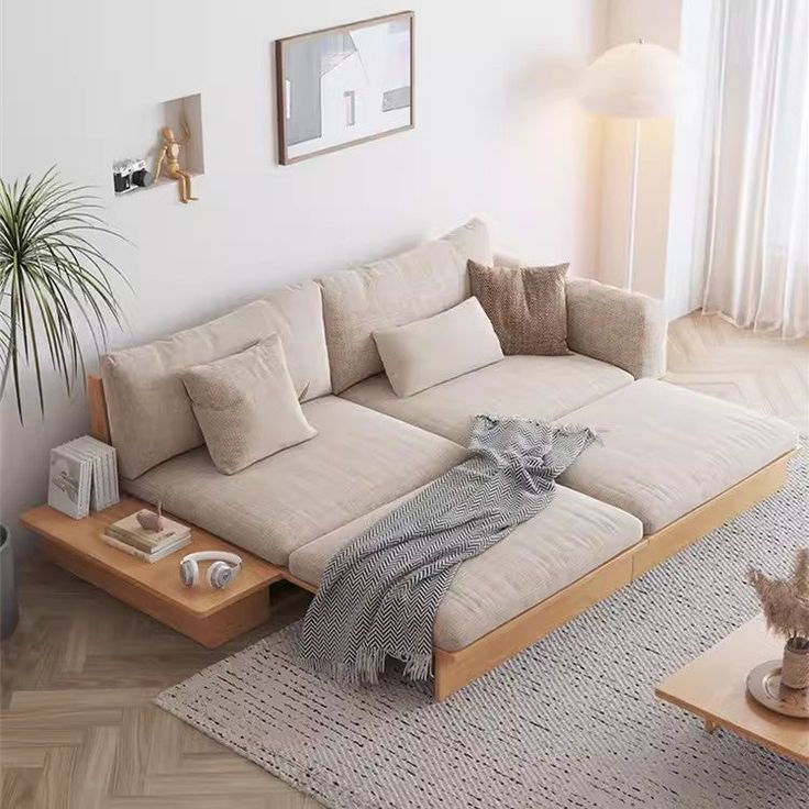 a living room with a couch, coffee table and potted plant on the floor