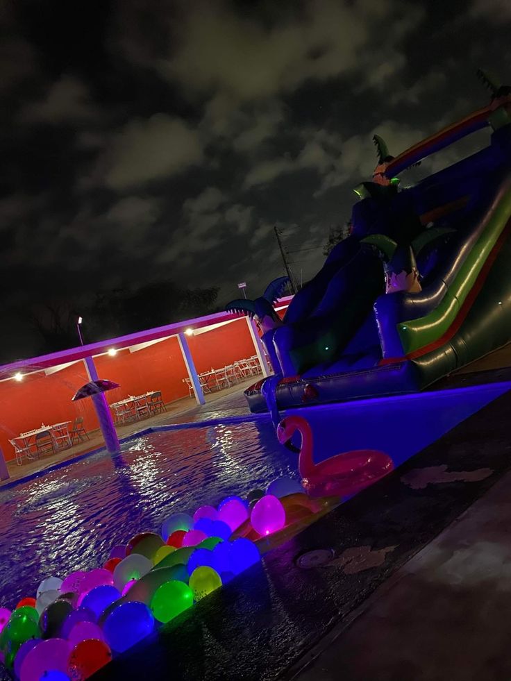 an inflatable water slide is lit up at night with colorful lights on it