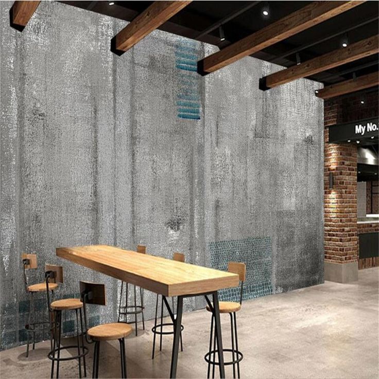 an empty room with several stools and a table in the center, next to a brick wall