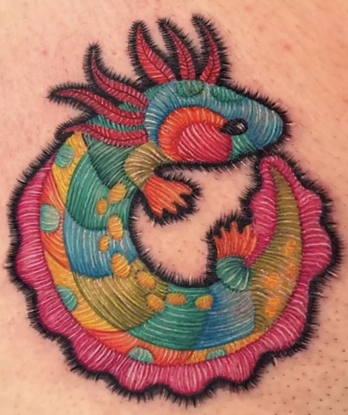 a colorful tattoo design on the back of a woman's shoulder