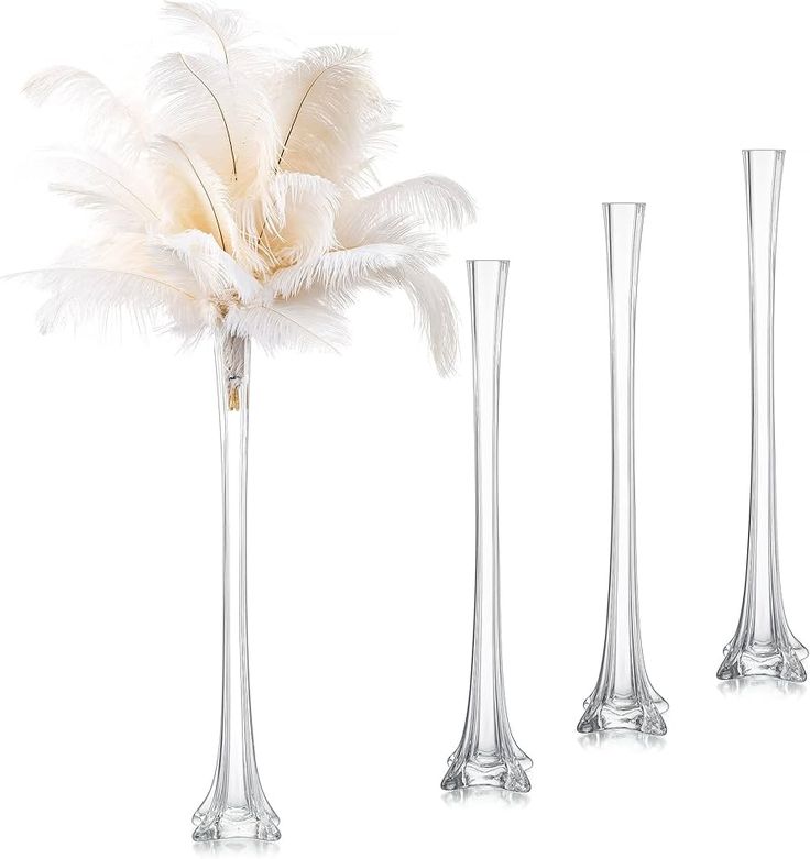 three tall vases with feathers in them on a white background, one is empty