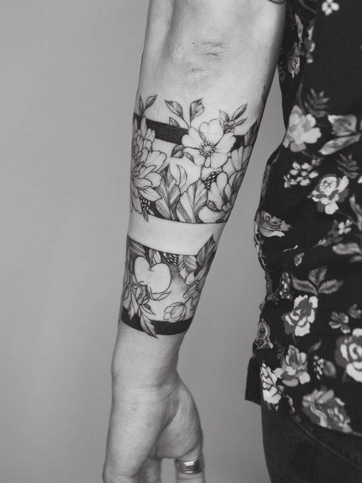 a woman's arm with flowers on it and a black and white photo behind her