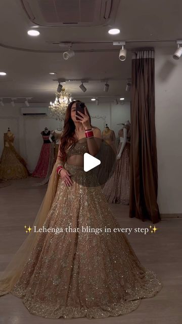 a woman in a gold gown taking a selfie with her cell phone while looking at dresses on mannequins