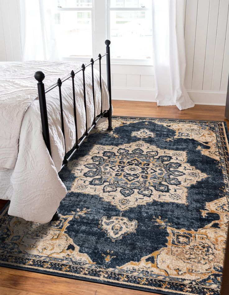 a bed with a blue and white rug on top of it next to a window