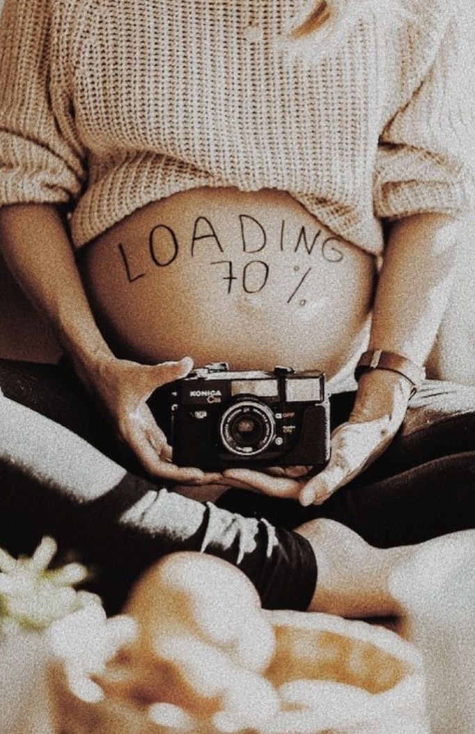 a pregnant woman holding a camera with the words loading 40 written on her stomach