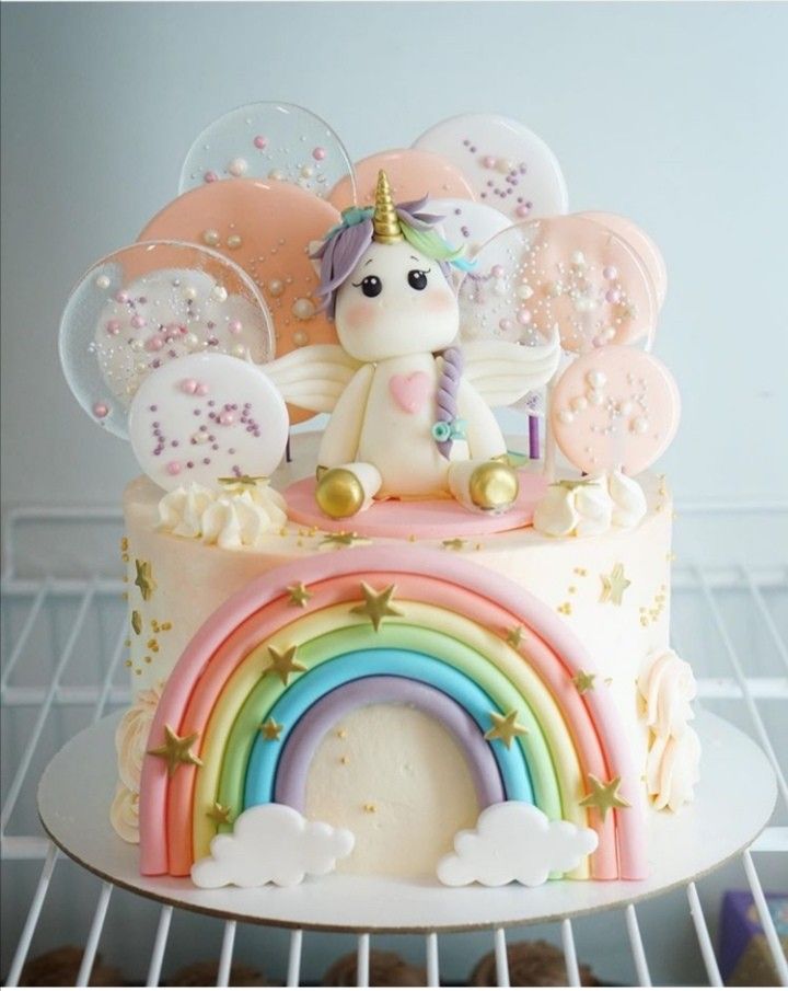 a birthday cake decorated with an unicorn and rainbow