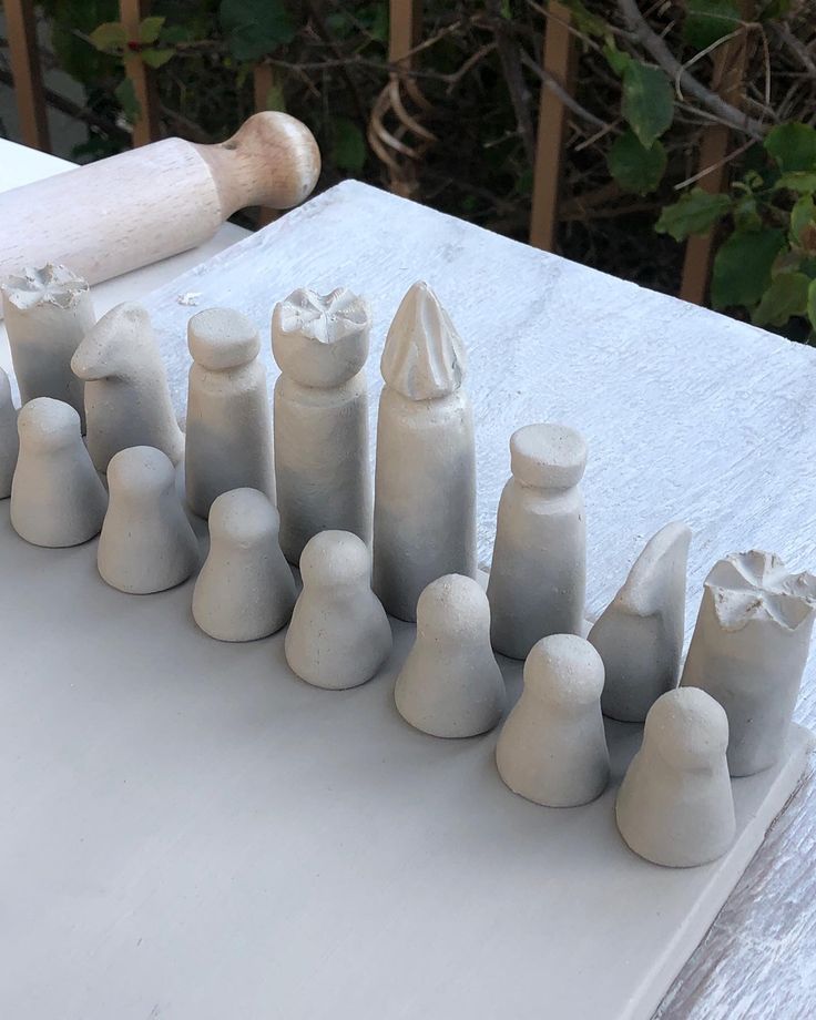 a group of clay figures sitting on top of a white table next to a wooden rolling pin