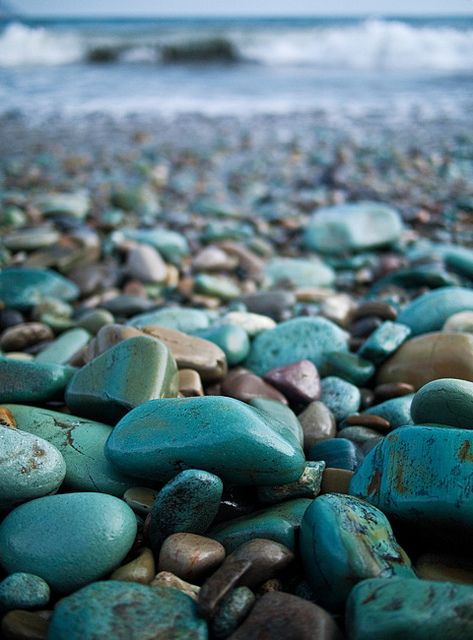 rocks and pebbles on the beach with waves in the background