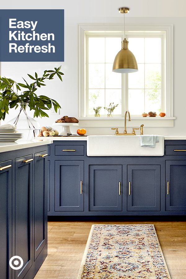 a kitchen with blue cabinets and an area rug in front of the sink, window