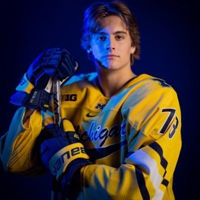 a young man in yellow jersey holding a hockey stick