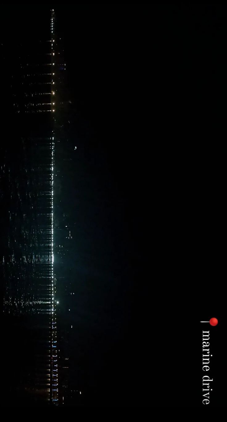 a very tall building lit up in the night sky with lights shining down on it