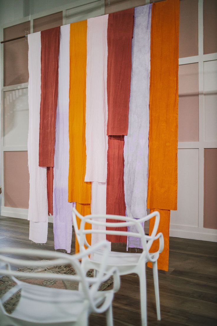 chairs and tables are lined up in front of colorful striped wall paper hanging from the ceiling