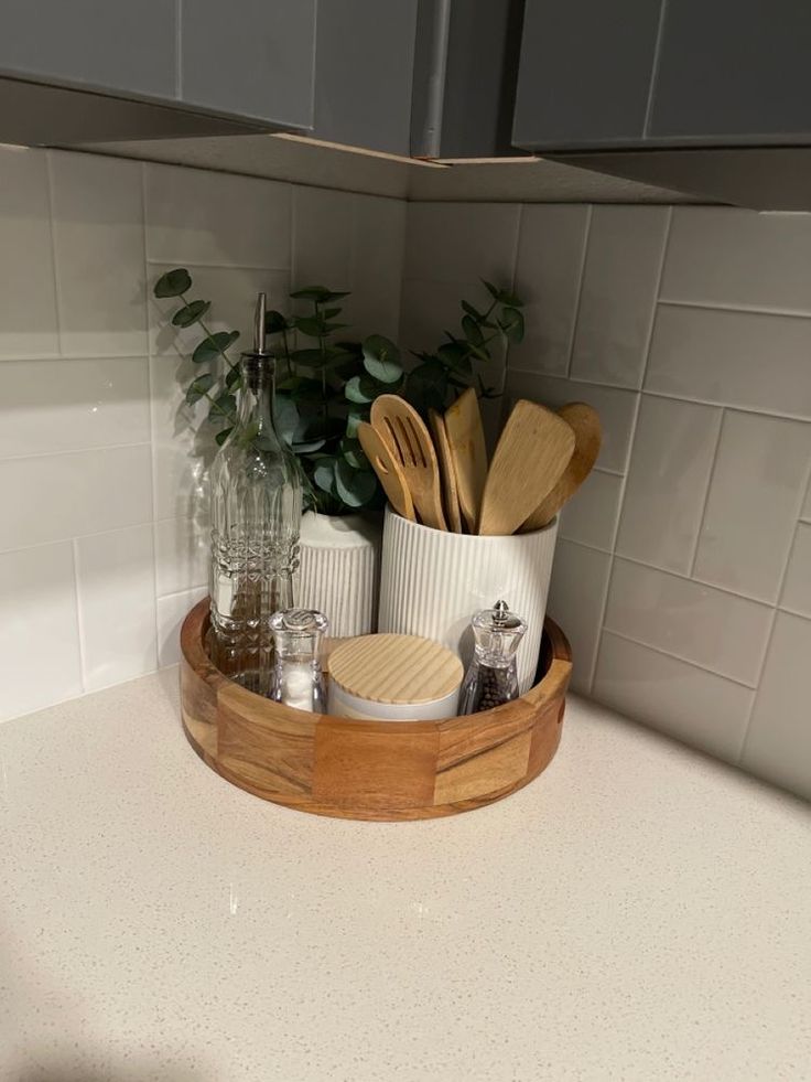 a wooden tray with utensils and spoons in it on a kitchen counter