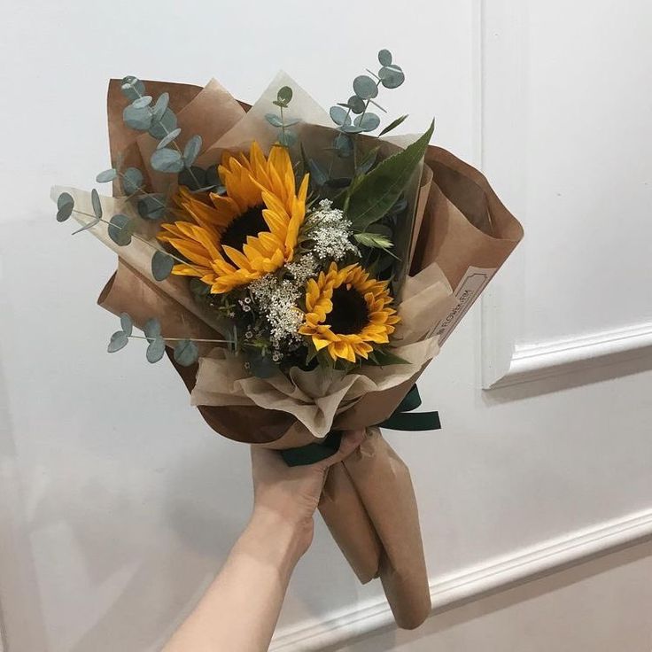 a bouquet of sunflowers is being held up by someone's hand in front of a door