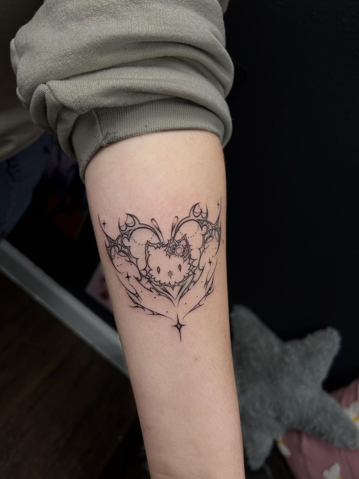 a woman's arm with a heart shaped tattoo on the left side of her arm