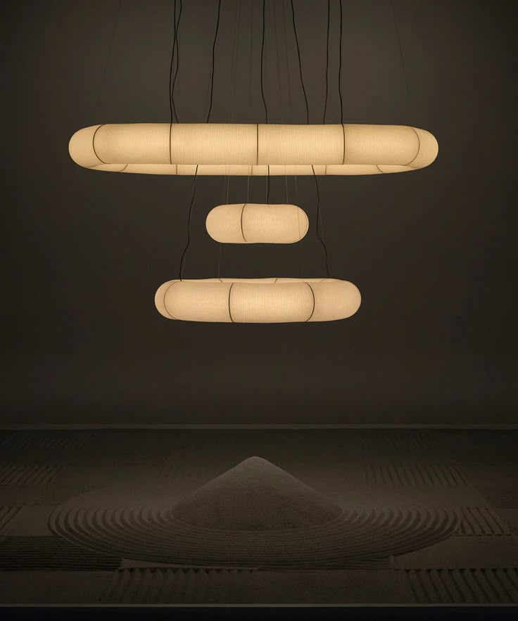 three suspended lights in the middle of a room with black walls and flooring on either side