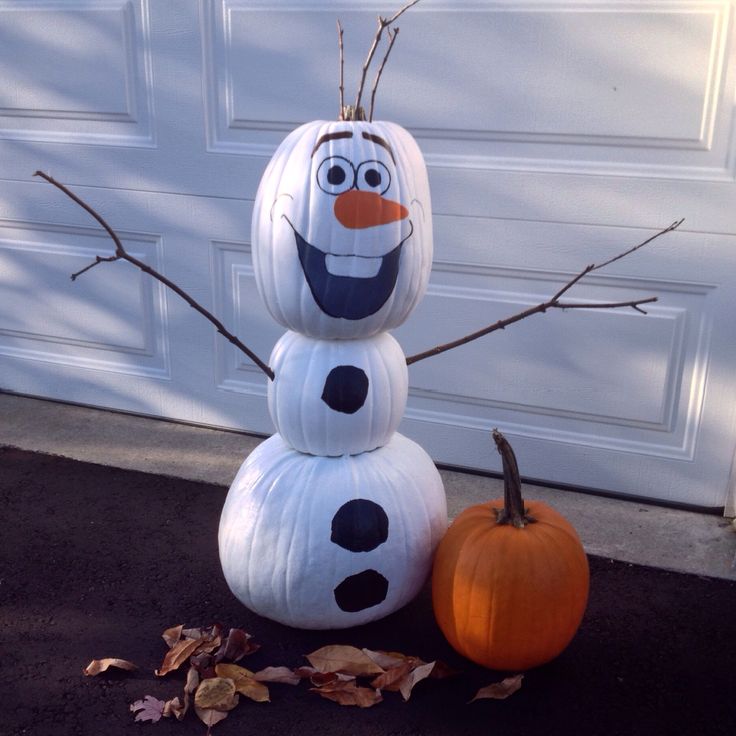 a snowman made out of pumpkins sitting on the ground next to a garage door