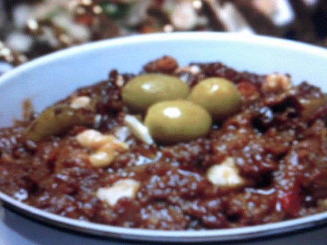 a white bowl filled with meat and olives