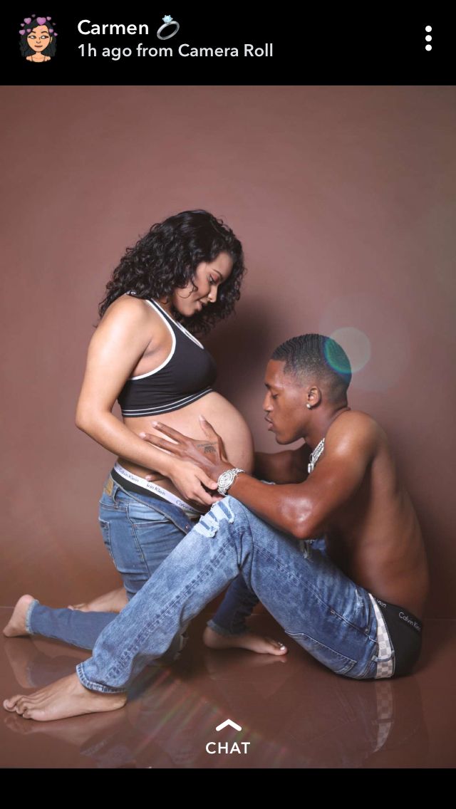 a pregnant woman sitting on the floor next to a man who is holding his belly