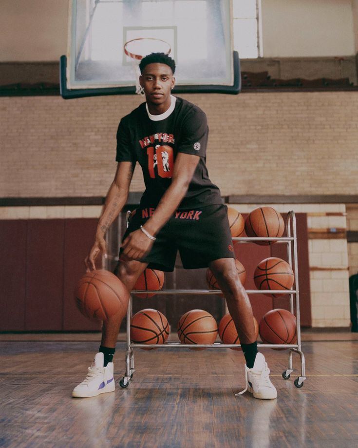 a young man holding a basketball on top of a hard wood floor in a gym