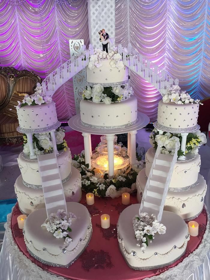 the wedding cake is decorated with white flowers and ribbons on it's tiers