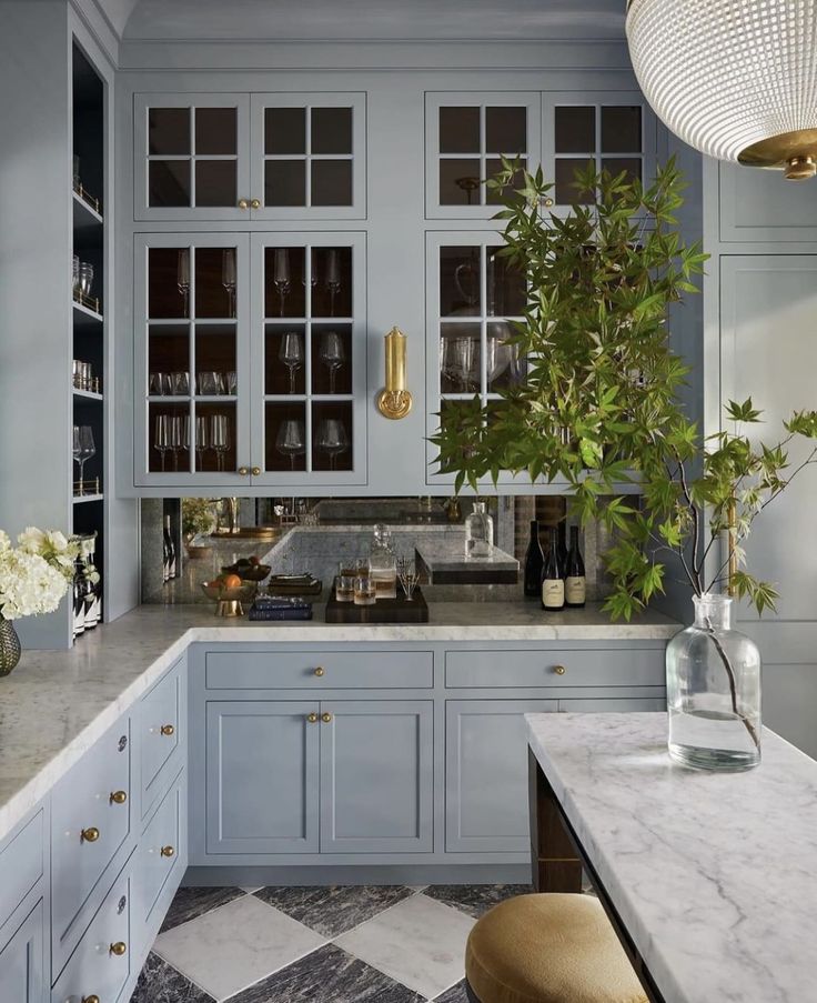 a kitchen with blue cabinets and marble counter tops, an island in the middle has a potted plant on it