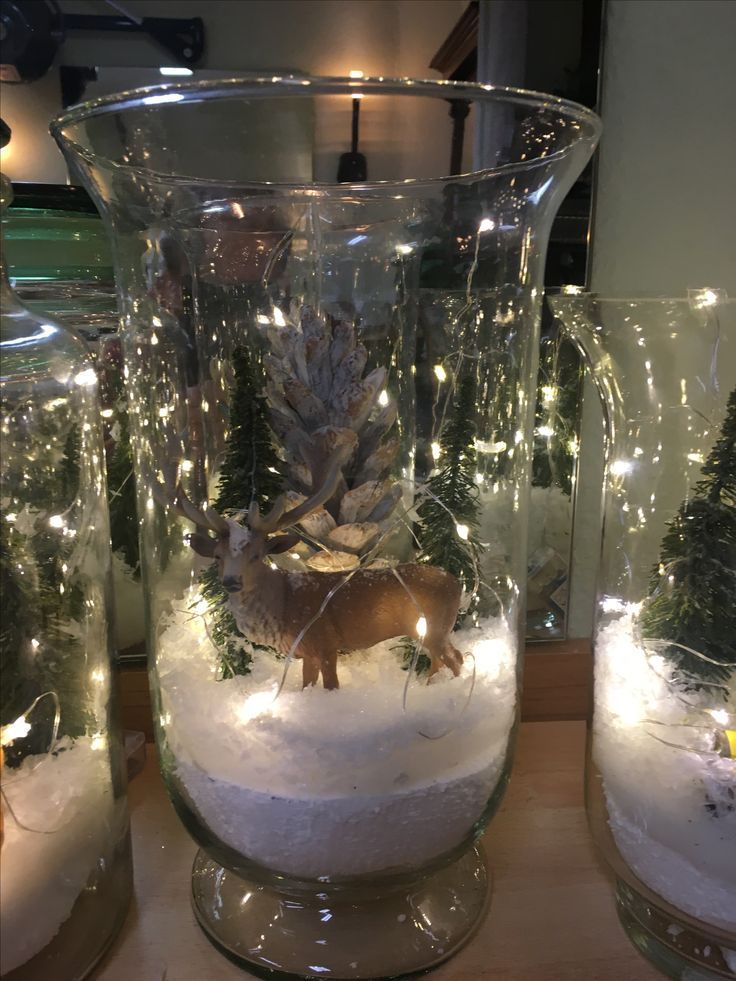 three glass vases filled with snow and christmas lights