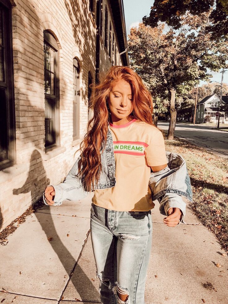 a woman walking down the sidewalk with her hand in her pocket and wearing a t - shirt that says no dreams