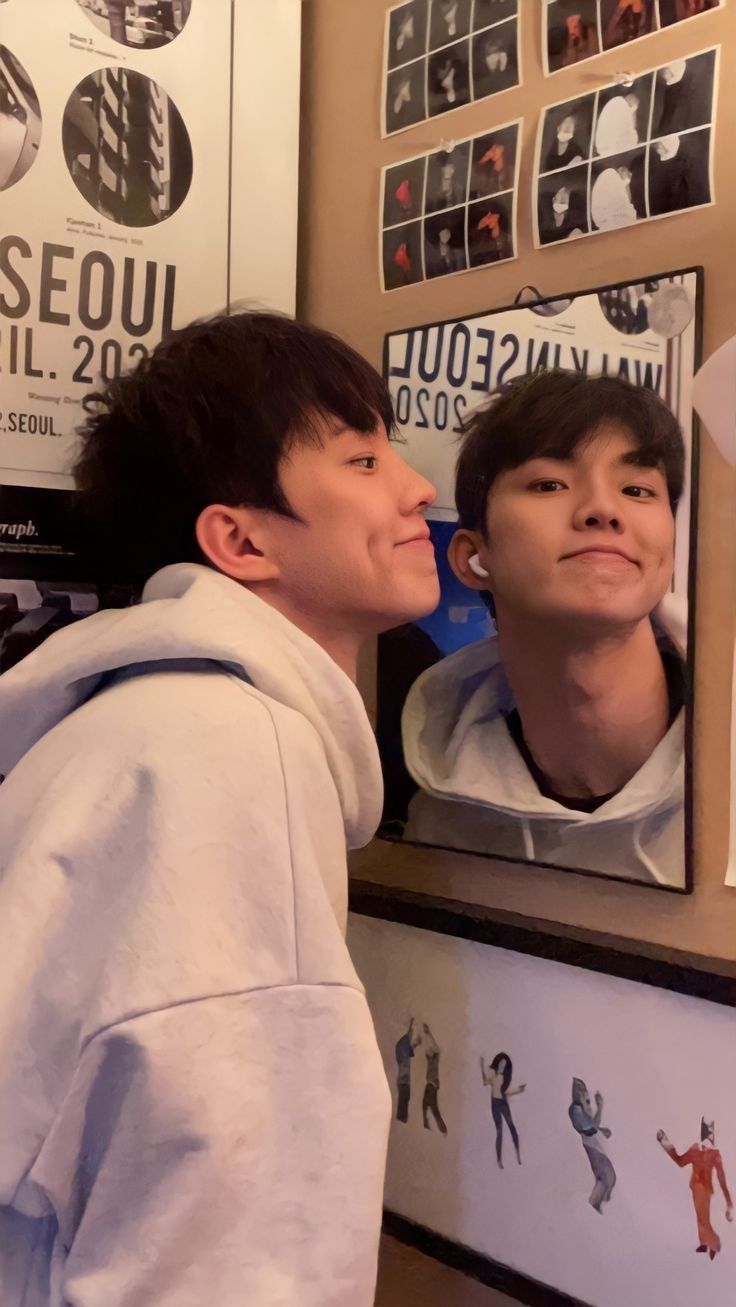 two young men standing in front of a mirror with their faces close to each other