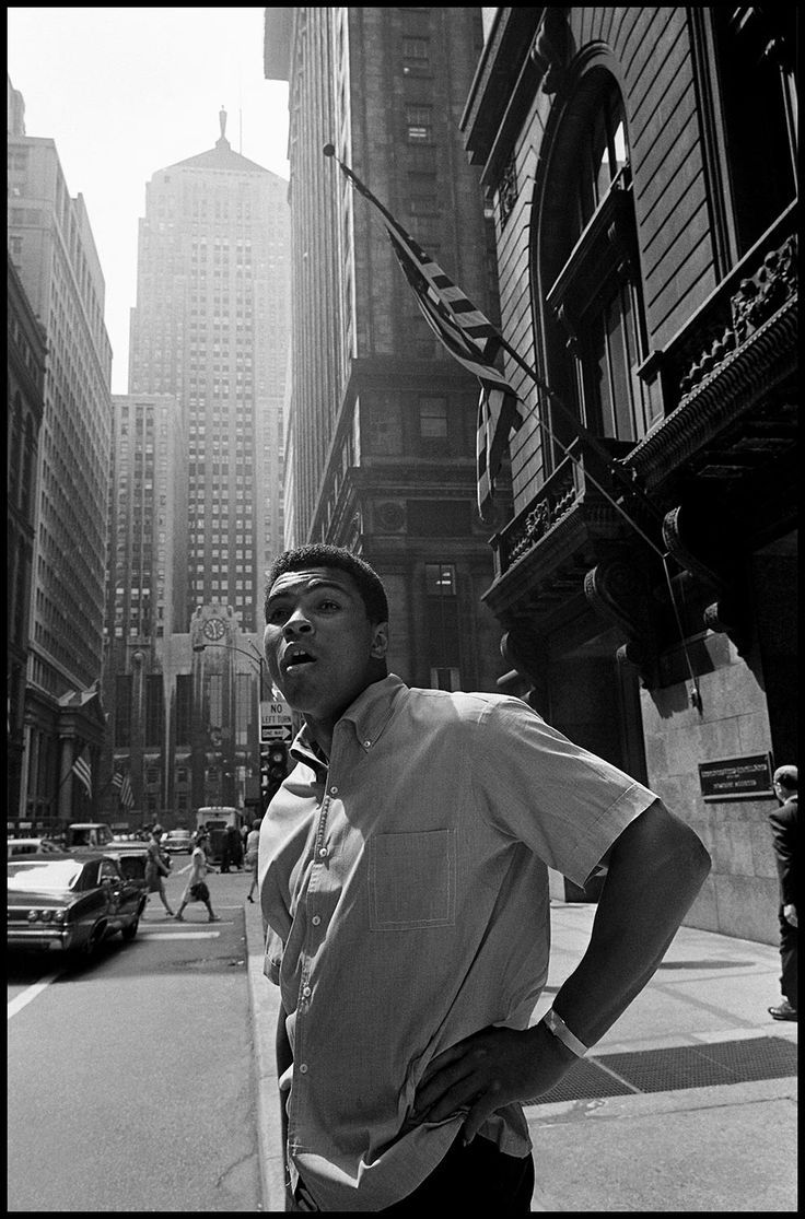 a man standing on the side of a street next to tall buildings in new york city