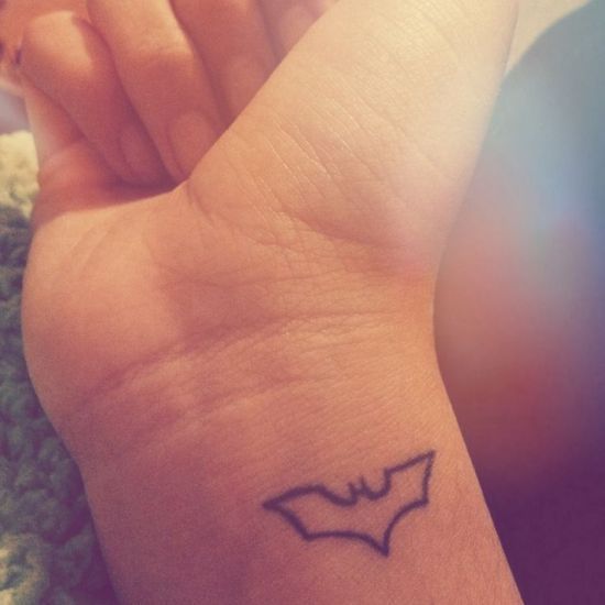 a small tattoo on the wrist of a person with a bat drawn on it's arm