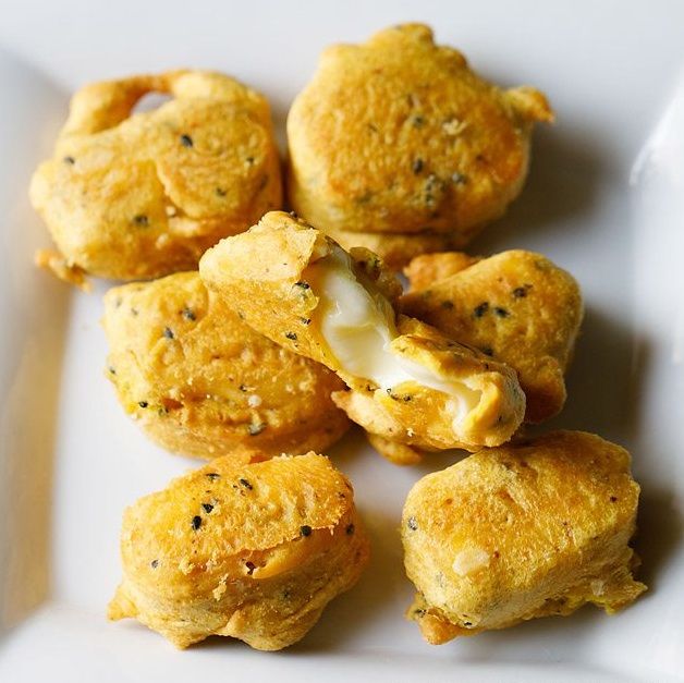 several small pastries on a white plate with a fork next to them and some cheese in the middle