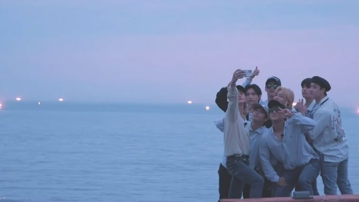 a group of people standing next to each other near the ocean