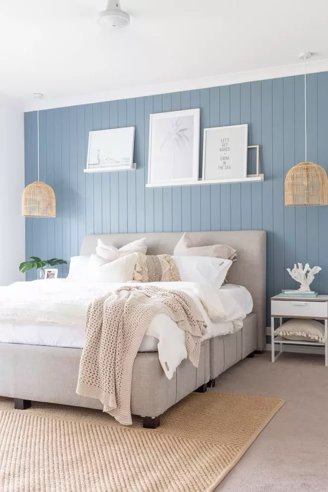 a bedroom with blue walls and white bedding in the center, along with pictures on the wall